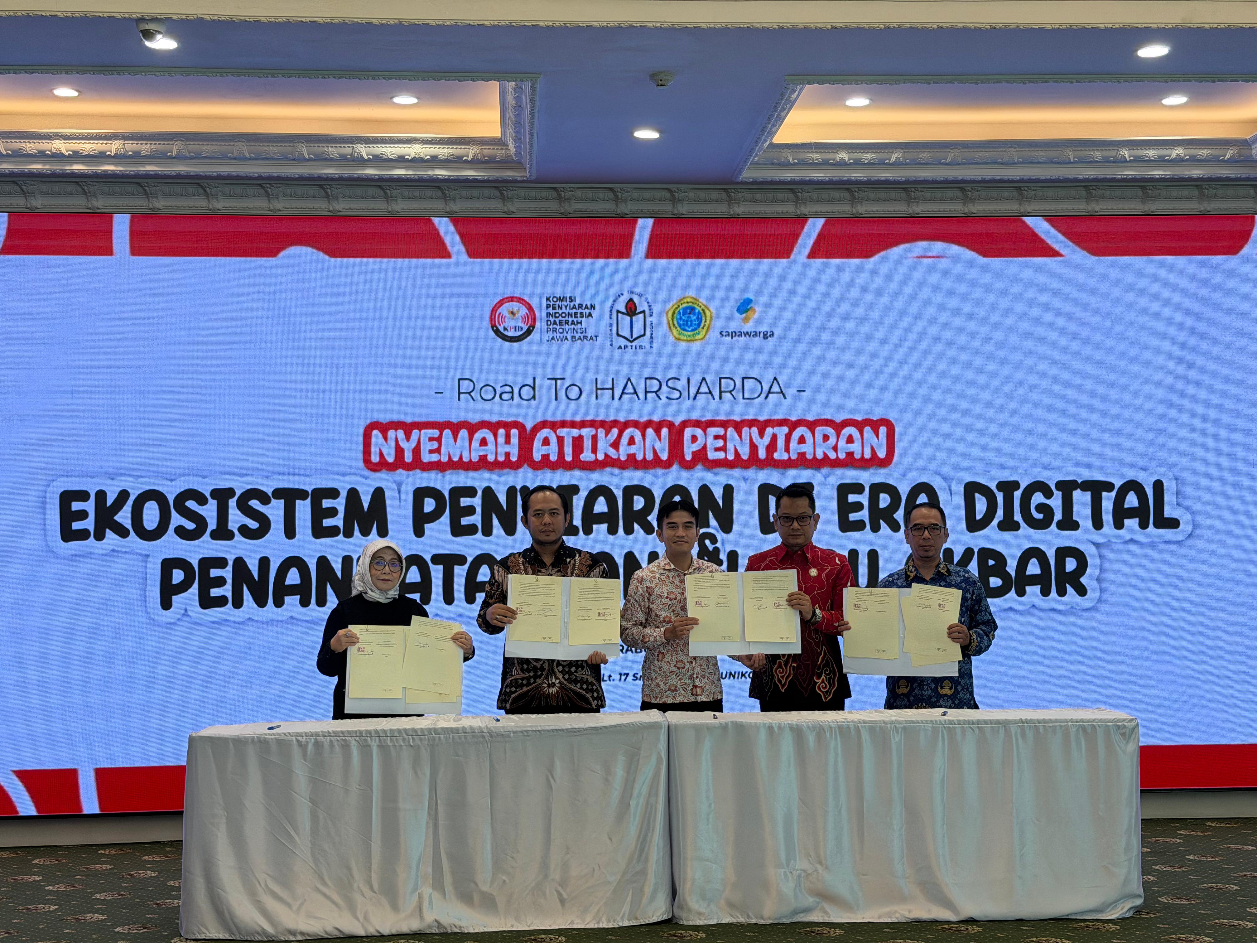 Ketua Bawaslu Provinsi Jawa Barat, H. Zacky Muhammad Zam Zam (kedua dari kiri), dan Ketua KPID Provinsi Jawa Barat, Dr. Adiyana Slamet, S.IP., M.Si. (kedua dari kanan), bersama sejumlah pimpinan lembaga mitra strategis menunjukkan dokumen Nota Kesepahaman (MoU) Akbar usai prosesi penandatanganan di Auditorium Lt. 17 Smart Building UNIKOM, Kota Bandung, Rabu (20/5/2026)
